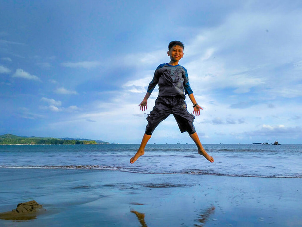 TULUNGAGUNG, INDONESIA - Nov 08, 2017: Child on beautiful beach. Little boy running and jumping at sea shore. Ocean vacation with kid - Foto, Imagen