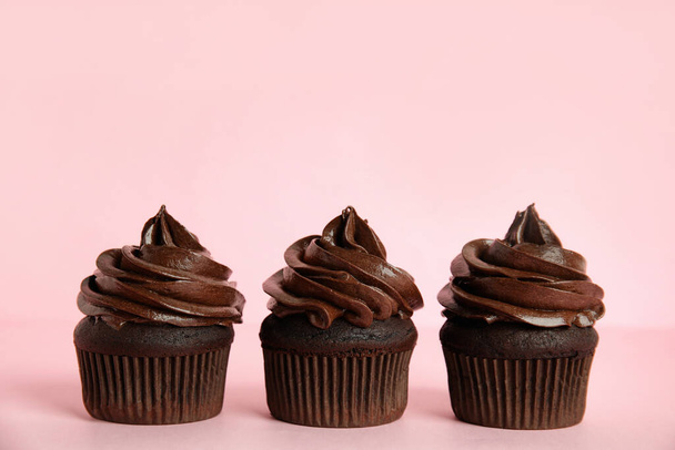 Delicious chocolate cupcakes with cream on pink background. Space for text - Fotó, kép