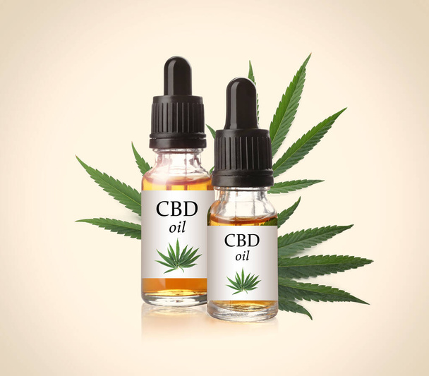 Bottles of cannabidiol tincture and hemp leaves on beige background - Foto, afbeelding
