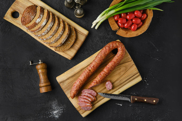 Overhead view of smoked lamb sausage rings on wooden cutting board on kitchen table  - Φωτογραφία, εικόνα