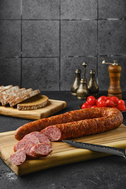Smoked beef sausage rings on wooden cutting board on kitchen table  - Foto, immagini