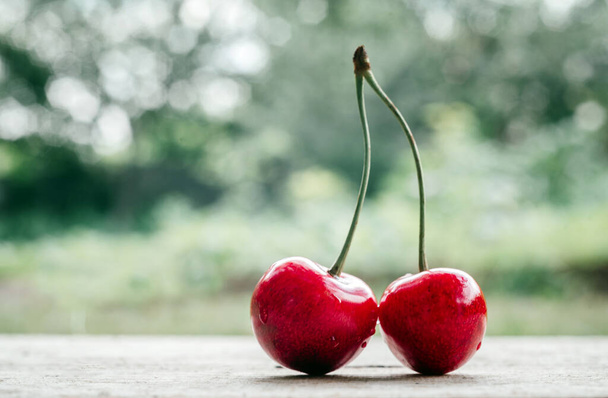 Ripe sweet cherry close-up on summer green bokeh background, summer fruits high on vitamins and antioxidants - Foto, imagen