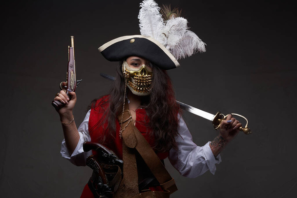 Piratin mit goldener Maske vor dunklem Hintergrund - Foto, Bild