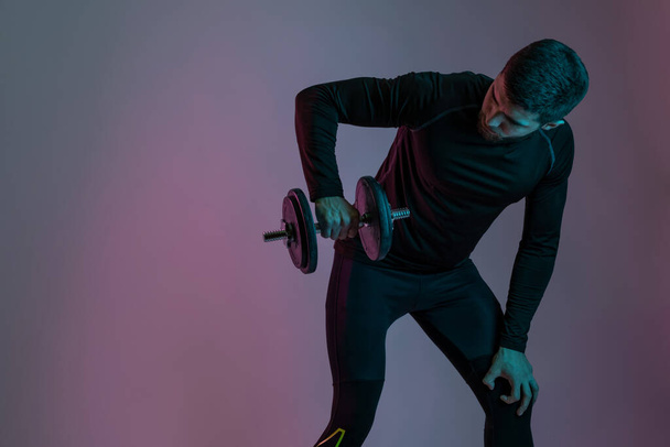 Мускулистый парень накачивает мышцы плеч гантели - Фото, изображение