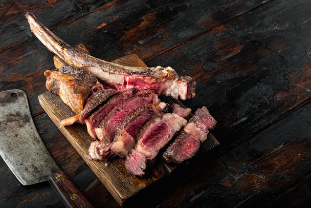 Traditional barbecue dry aged wagyu tomahawk steak sliced set, on wooden serving board, on old dark  wooden table background, with copy space for text - Photo, Image