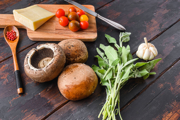 Portabello champignons ingrédients pour la cuisson, fromage cheddar, tomates cerises et sauge sur un vieux fond de bois sombre, vue de côté - Photo, image