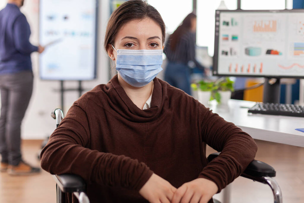 Woman employee with disabilities with protection mask looking at camera - Photo, Image
