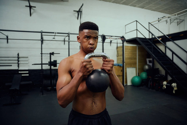 African American male doing cross training in gym. Mixed race male using a kettlebell during exercise. High quality photo - Φωτογραφία, εικόνα