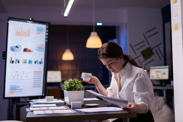 Работающая бизнесвумен просматривает отчеты презентации на мониторе по сравнению с финансовой картой - Фото, изображение