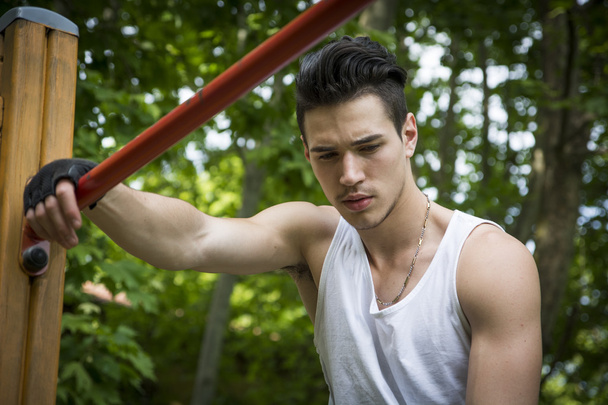 Handsome young man exercising in outdoor gym in park - Fotografie, Obrázek