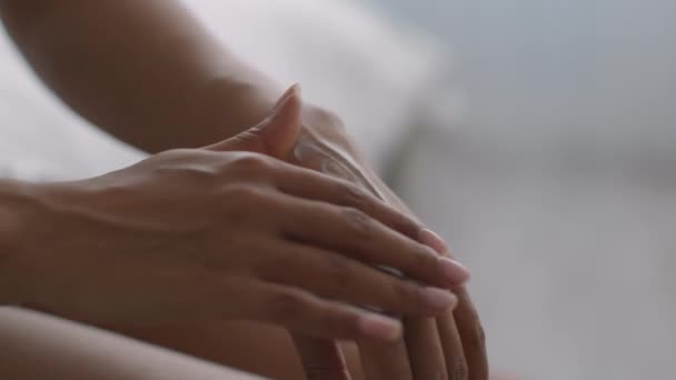 Procedimientos de cuidado de la piel. Primer plano de irreconocible dama afroamericana aplicando crema hidratante en la piel de sus manos - Metraje, vídeo