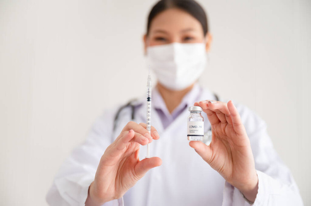 La dottoressa porta una siringa e un vaccino contro il COVID-19, la vaccinazione e gli esperimenti di laboratorio. Concetto di prevenzione della diffusione di COVID-19. - Foto, immagini