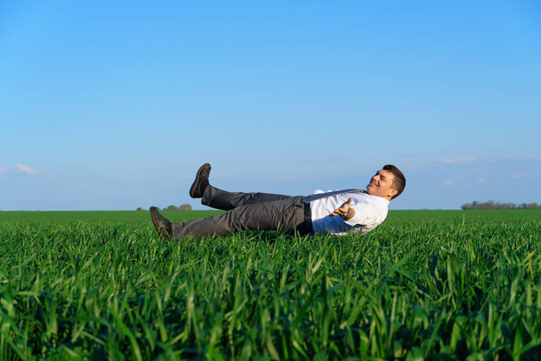 Geschäftsmann simuliert Flug auf der grünen Wiese, Geschäfts- und Freiheitskonzept, grünes Gras und blauer Himmel als Hintergrund - Foto, Bild
