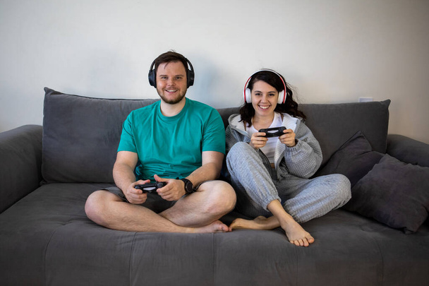 couple playing video games together sitting on sofa couch - Photo, Image