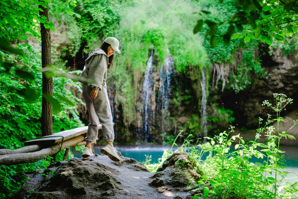 女性ハイカーは滝の景色を楽しむ夏の旅行のコンセプト - 写真・画像
