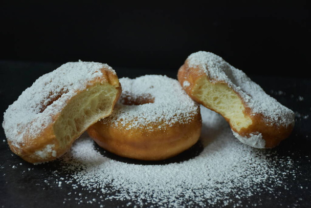Donut und Puderzucker auf schwarzem Hintergrund, - Foto, Bild