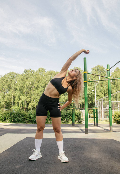 A blonde girl in a sports uniform performs fitness exercises on a workout - Fotografie, Obrázek