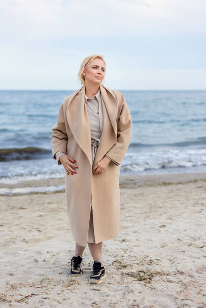 Woman in coat by the sea - Foto, afbeelding
