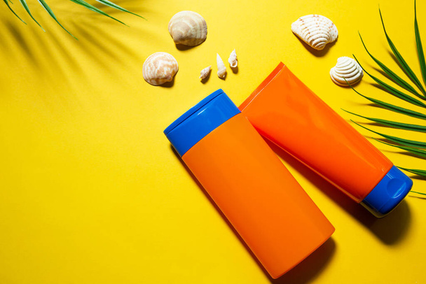 Two tubes with mock up sunscreens on a yellow summer background. UV protection of the skin with an SPF filter, hair care-shampoo and conditioner. A safe tan on the beach. Flat lay - resort on the sea. - Photo, Image