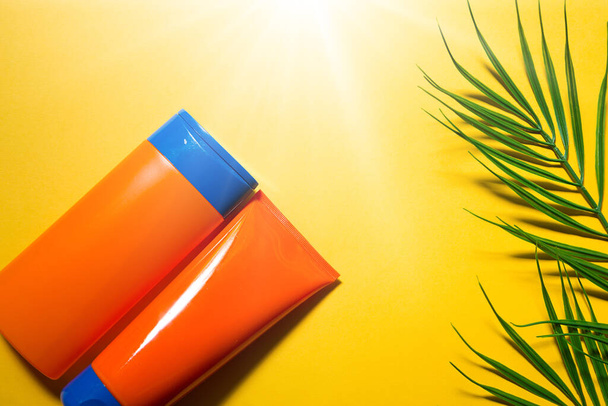 Two tubes with mock up sunscreens on a yellow summer background. UV protection of the skin with an SPF filter, hair care-shampoo and conditioner. A safe tan on the beach. Flat lay - resort on the sea. - Fotografie, Obrázek