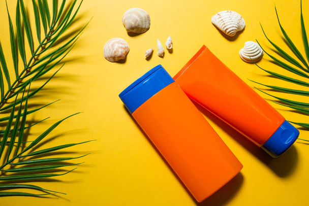 Two tubes with mock up sunscreens on a yellow summer background. UV protection of the skin with an SPF filter, hair care-shampoo and conditioner. A safe tan on the beach. Flat lay - resort on the sea. - Foto, afbeelding