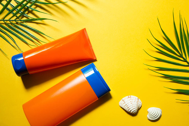 Two tubes with mock up sunscreens on a yellow summer background. UV protection of the skin with an SPF filter, hair care-shampoo and conditioner. A safe tan on the beach. Flat lay - resort on the sea. - Photo, Image