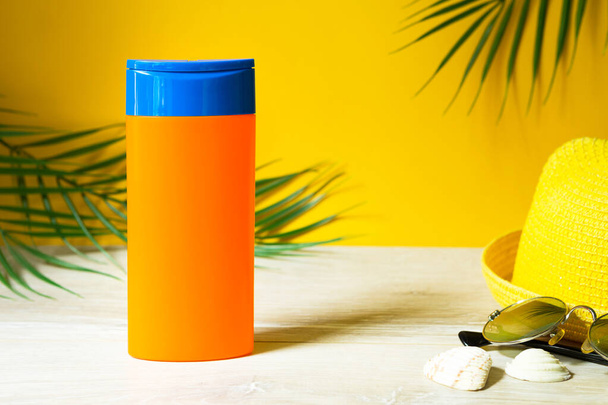 Tubes with mock up sunscreens on the table with yellow summer background. UV protection of the skin with an SPF filter, hair care-shampoo and conditioner. A safe tan on the beach, resort on the sea. - Фото, зображення