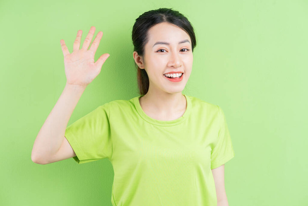 Young Asian woman wearing green shirt and posing on green background - Photo, Image