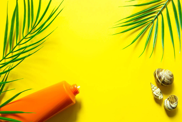 Tube of sunscreen on a yellow summer background with palm leaves and the sun. Tanning agent, skin protection, a trip to the sea, vacation on the beach, UV protection, SPF filter. Flat lay, copy space - 写真・画像