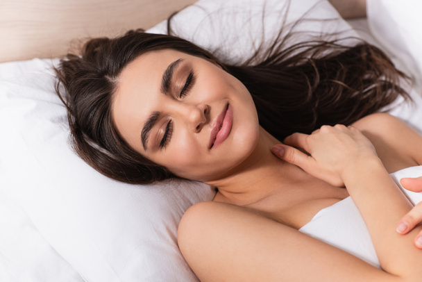 happy young woman with closed eyes lying on pillow - Fotoğraf, Görsel