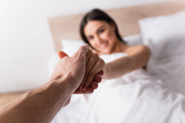 Мужчина, держащийся за руки с размытой девушкой в спальне - Фото, изображение