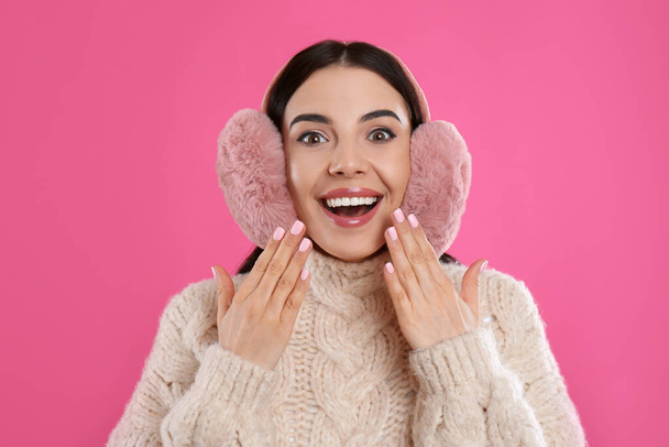 Beautiful young woman wearing earmuffs on pink background - Fotoğraf, Görsel