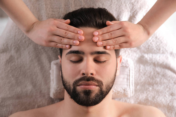 Young man receiving facial massage in beauty salon, top view - Foto, Bild