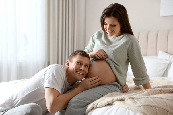 Young pregnant woman with her husband at home - Фото, изображение