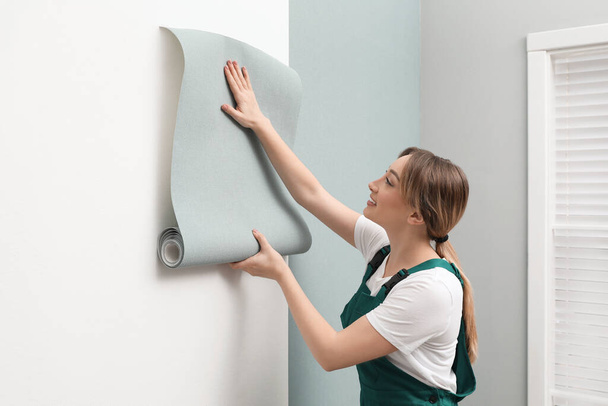 Worker hanging stylish wall paper sheet indoors - Foto, imagen