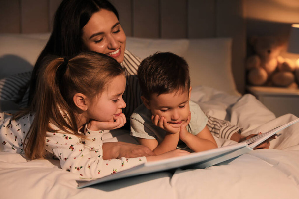 Mother reading bedtime story to her children at home - Φωτογραφία, εικόνα