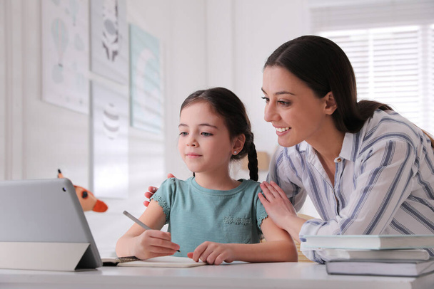 Mother helping her daughter doing homework with tablet at home - Φωτογραφία, εικόνα