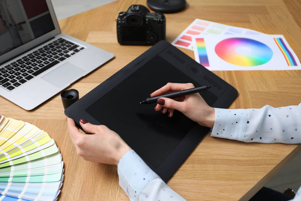 Professional designer with graphic tablet at wooden table, closeup - Fotó, kép