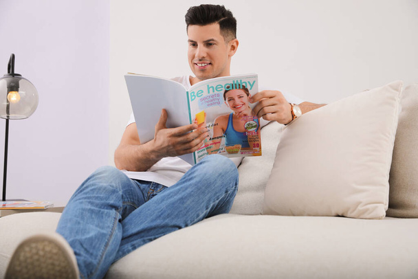 Man reading magazine on sofa in living room - Foto, Imagem