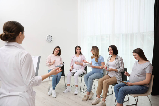 Group of pregnant women with doctor at courses for expectant mothers indoors - Фото, изображение