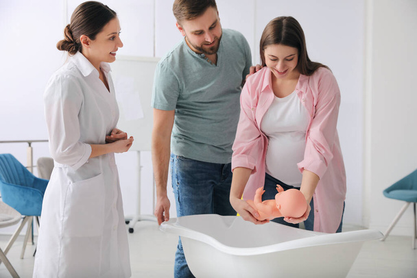Man with pregnant wife learning how to bathe baby at courses for expectant parents indoors - Zdjęcie, obraz
