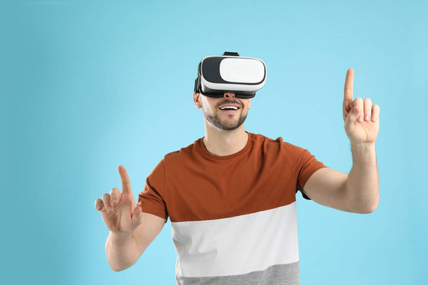 Man using virtual reality headset on light blue background - Foto, Bild