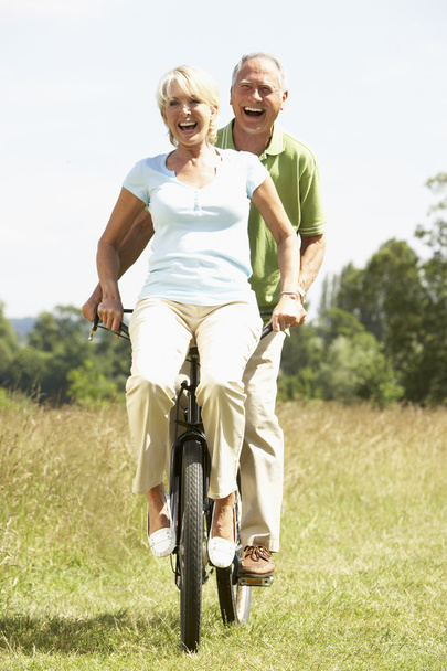 Mature couple riding bike in countryside - Foto, afbeelding