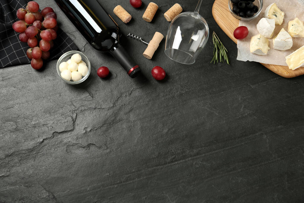 Flat lay composition with red wine and snacks on black table, space for text - Photo, image