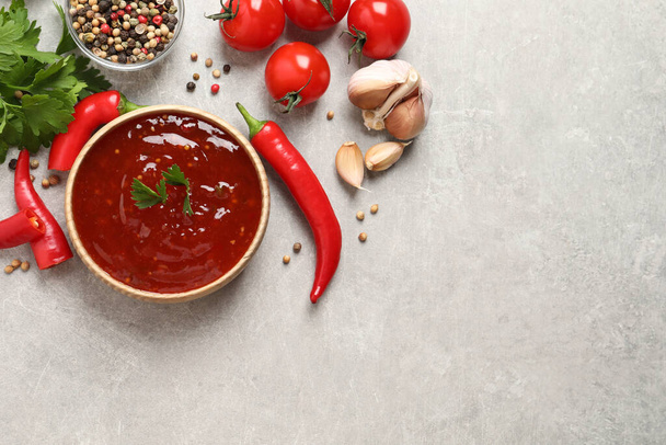 Spicy chili sauce and ingredients on light grey table, flat lay. Space for text - Fotó, kép