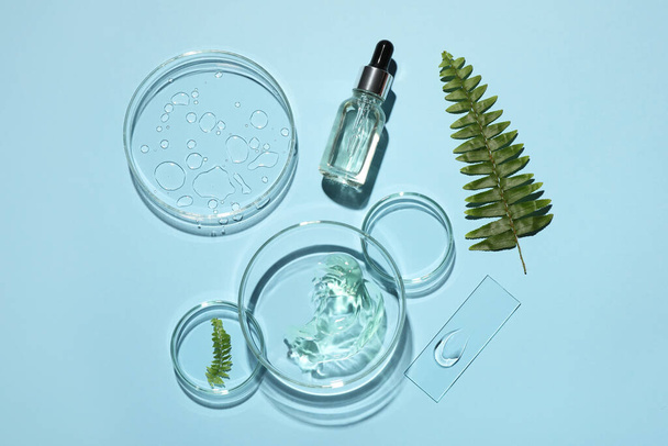 Flat lay composition with cosmetic product, fern and laboratory glassware on light blue background - Фото, зображення