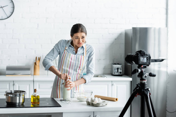 housewife opening bottle of milk in front digital camera in kitchen - Foto, Imagem