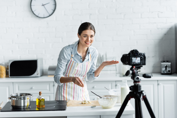 blogueur culinaire joyeux pointant avec la main près de la pâte et appareil photo numérique floue - Photo, image