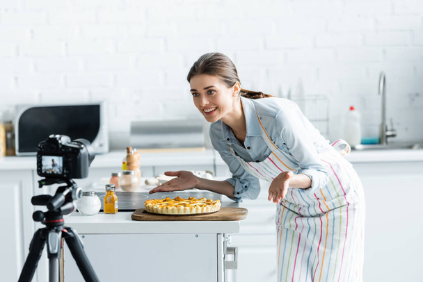 blogueur culinaire heureux pointant avec les mains à tarte délicieuse près floue appareil photo numérique - Photo, image