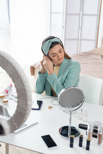 young beauty blogger preparing for record near phone holder and containers with cosmetics - Fotografie, Obrázek